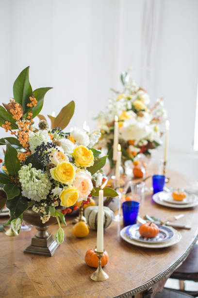 istock Luxurious elegant wedding decor in autumn style. Wooden vintage table setting with ceramic plates and silver cutlery. Fresh flowers in a vase, orange pumpkins, deer horns and candles. Romantic dinner. 1175011246