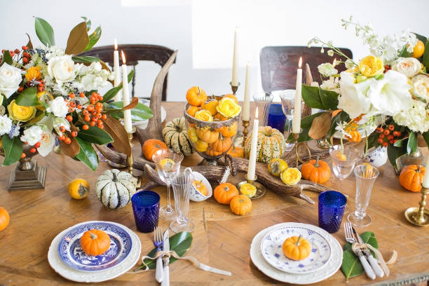istock Luxurious elegant wedding decor in autumn style. Wooden vintage table setting with ceramic plates and silver cutlery. Fresh flowers in a vase, orange pumpkins, deer horns and candles. Romantic dinner. 1175011326