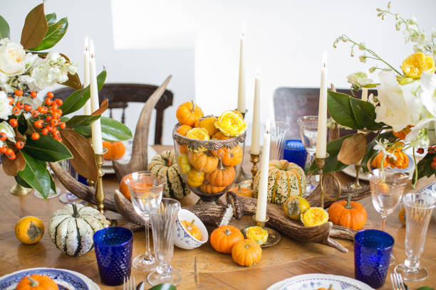 istock Luxurious elegant wedding decor in autumn style. Wooden vintage table setting with ceramic plates and silver cutlery. Fresh flowers in a vase, orange pumpkins, deer horns and candles. Romantic dinner. 1175011385
