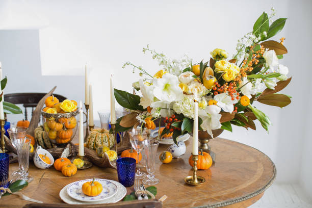 luxurious elegant wedding decor in autumn style. wooden vintage table setting with ceramic plates and silver cutlery. fresh flowers in a vase, orange pumpkins, deer horns and candles. romantic dinner. - autumn table setting flower imagens e fotografias de stock