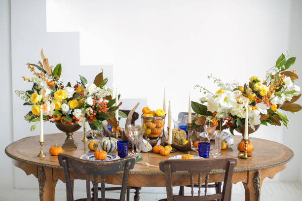 istock Luxurious elegant wedding decor in autumn style. Wooden vintage table and chairs setting with ceramic plates and silver cutlery. Fresh flowers in a vase, orange pumpkins, deer horns and candles. 1175011502