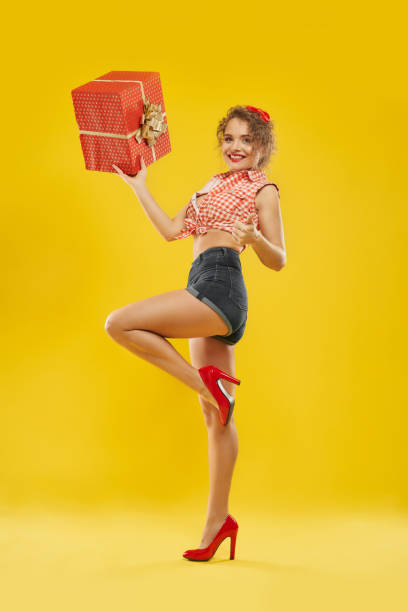 istock Lady standing on one leg holding red box with golden bow. 1175014619
