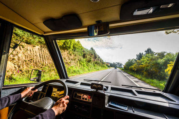 Woman is driving motorhome or campervan on the road outdoors in nature. Motorhome is following a campervan on adventure family trip or journey in nature in Galicia Spain. Exploring on active vacation