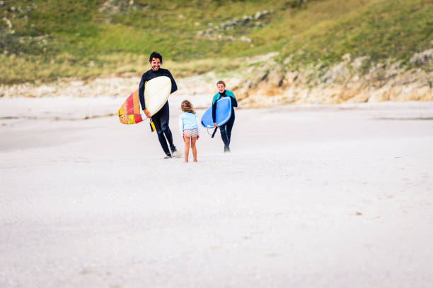 istock Surfing family with surfboard is walking on the sandy beach. 1175014823