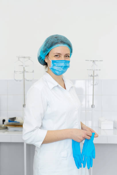 istock Nurse in scrub and mask puts gloves on her hands 1175016878