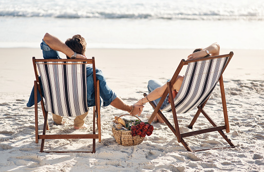 Rearview shot of a middle aged couple sitting in their beach chairs on the the beach