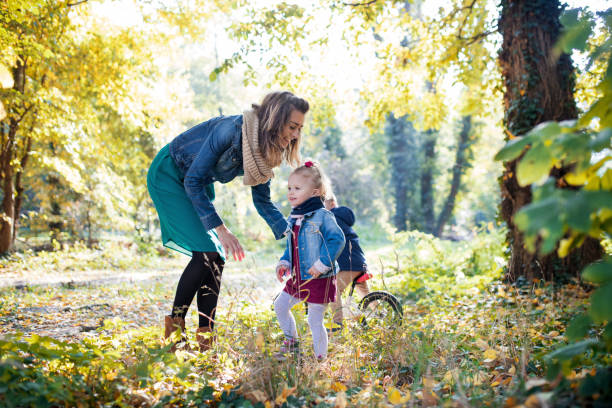 beautiful young mother with small twins on a walk in autumn forest. - twin falls imagens e fotografias de stock