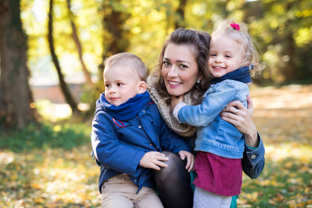 istock Beautiful young mother with small twins on a walk in autumn forest. 1175018039
