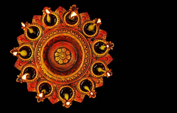Plate of lit diyas - concept of prayer, worship, and celebrations, symbol of peace and hope. Black background. Apt for Diwali, Deepawali, Durga pooja, Rakshabandhan, Raakhi, Ganesh Chaturthi Onam, Inauguration, opening of an event, festival, festivals. No people, no text, copy space, copyspace. Black background.