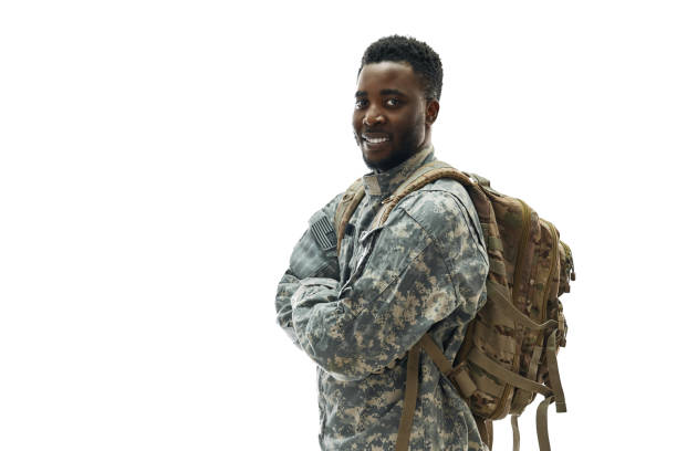 Positivity American ranker with big backpack confidently standing with crossed hands and smiling at camera. African soldier wearing army uniform , preparing for operation. Concept of American army.