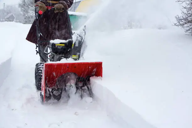 A man clears snow with a snow blower after a snowfall