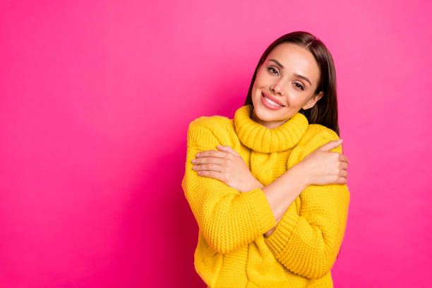 istock Portrait of charming youth hugging herself looking with beaming smile wearing yellow pullover isolated over fuchsia background 1175020964