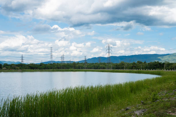 istock Reservoir are surrounded by green pastures with high voltage pole and sky, clouds. 1175021377