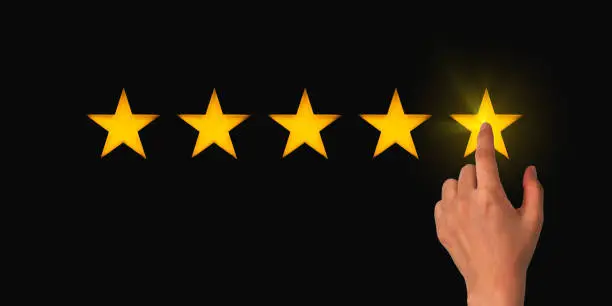 Photo of A woman clicks on a star rating, the concept of a positive rating, reviews and feedback. Black background