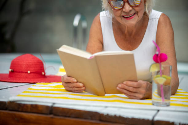 istock Joyful old woman reading book and smiling 1175024656