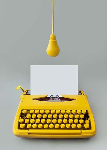 Retro typewriter with yellow hanging light bulb, inspiration, new idea