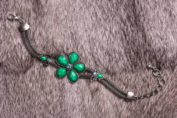 Beautiful female bracelet with precious stones lying on gray fur.