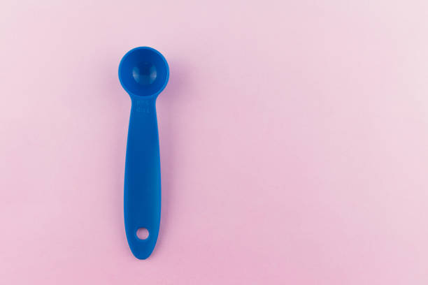 istock measuring spoon of plastic on pink background. 1175029834