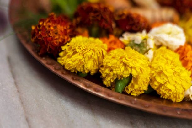 Closeup horizontal side angle shot of marigold flowers on a thali or plate for puja preparations. Background picture of Hindu traditional rituals with copy space.