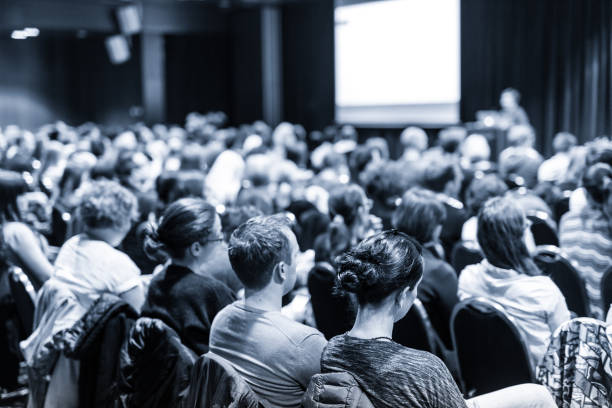 Speaker giving presentation on scientific business conference. Business and entrepreneurship symposium. Speaker giving a talk at business meeting. Audience in conference hall. Rear view of unrecognized participant in audience. meeting stock pictures, royalty-free photos & images