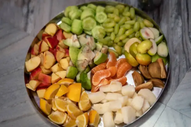 A plate or thali full of fruits such as orange, apple, cucumber, grapes, jicama etc for pooja or puja prasad. Background picture for tropical fruit bowl huge.