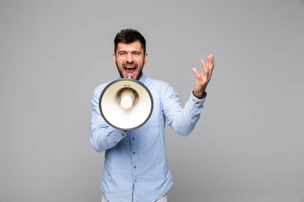istock Angry man shouting through megaphone against gray background 1175031798