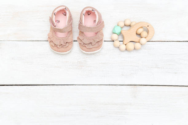 istock Baby pink sandals, socks and teether on a wooden background. Copy space 1175032476
