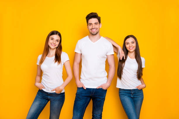 portrait of cheerful ladies with guy having long attractive ginger hair putting their hands in pockets isolated over yellow background - long hair red hair women men imagens e fotografias de stock