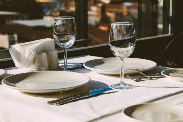 istock Table setting in restaurant. Empty wine glasses, plates, forks, knifes on the tablecloth. Elegant restaurant interior. 1175038898