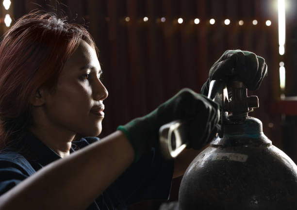 Diverse Female workshop engineer adjusting valves on gas tanks stock photo