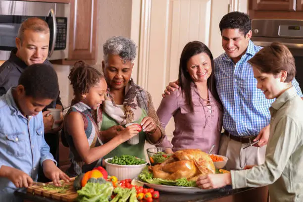 Photo of Diverse family in home kitchen cooking Thanksgiving dinner.