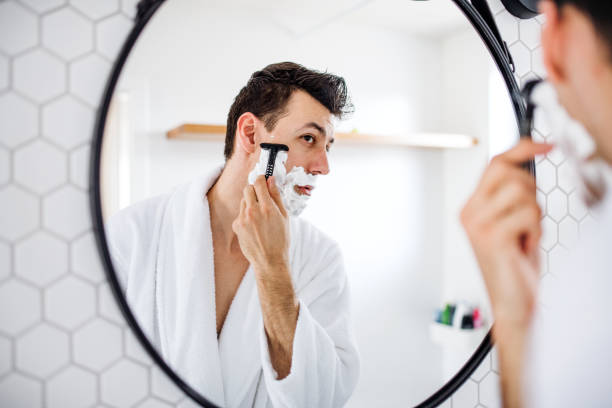 朝、毎日のルーチンでバスルームで剃る若い男。 - wet shave ストックフォトと画像