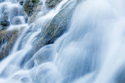 Close shot of freshwater of tropical waterfall pouring on limestone in rainy season, pure water flowing on layers of limestone wall. Long exposure.