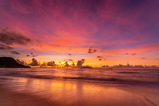 colorful sky over tropical island beach after sunset with reflections on sand beach, long exposure