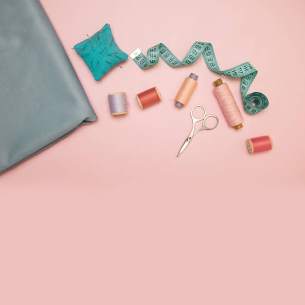 istock Sewing accessories and fabric on a pink background. Sewing threads, needles, fabric, buttons and sewing centimeter 1175050749