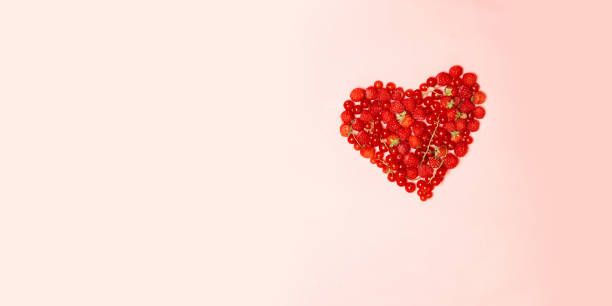 istock Various fresh summer berries in heart shapeon pink background. 1175050827