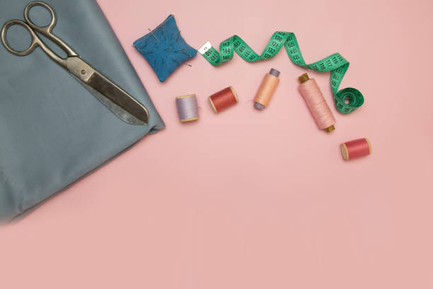 istock Sewing accessories and fabric on a pink background. Sewing threads, needles, fabric, buttons and sewing centimeter 1175050873