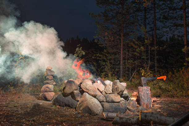 Fire burning at night next to a pyramid of stones and wooden chocks for the seat.