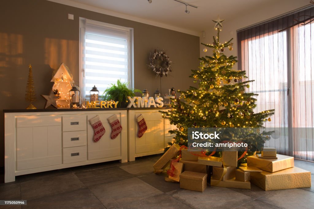 decorated christmas fir tree in apartment modern living room with christmas tree, presents and other festive decoration during day time Christmas Stock Photo