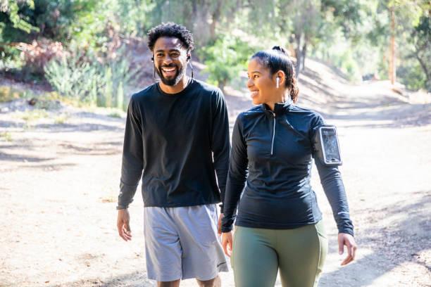 A black man and Latina woman walking on a trail after a workout