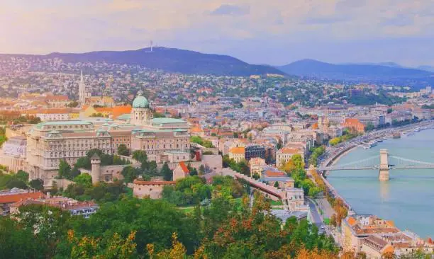 Photo of Budapest, Hungary. Beautiful aerial panoramic skyline view of historic Buda Castle Royal Palace and South Rondella with Szechenyi Chain Bridge over River Danube at sunrise with blue sky and clouds.