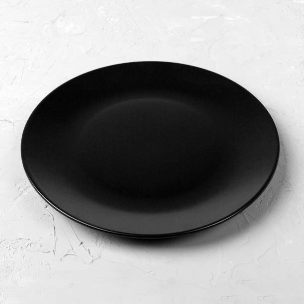 istock Black round plate on wooden background, top view, copy space 1175055935