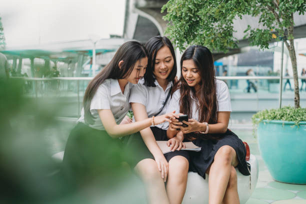 three student friends using a mobile phone together in the city - siam square imagens e fotografias de stock