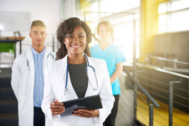 Portrait of a friendly female african american doctor and team in bright modern office stock photo