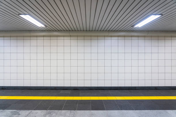 Closeup View of a Regular Public Corridor. Closeup View of a Regular Public Corridor. Nobody is in the Tunnel with White Square Tiles, Yellow Tactile Paving and White Ceiling Lights. subway platform stock pictures, royalty-free photos & images