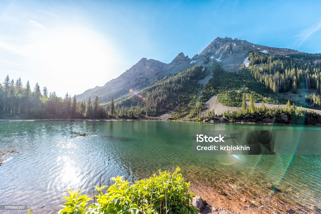 Maroon Bells rocky mountain snow peak view with Creater Lake in Colorado in summer wide angle view with bright sun and flare Colorado Stock Photo