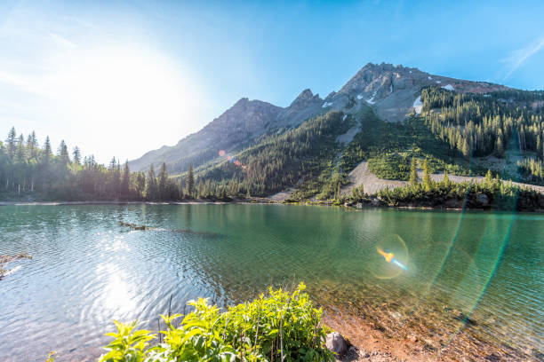 Maroon Bells rocky mountain snow peak view with Creater Lake in Colorado in summer wide angle view with bright sun and flare Maroon Bells rocky mountain snow peak view with Creater Lake in Colorado in summer wide angle view with bright sun and flare rocky mountains stock pictures, royalty-free photos & images