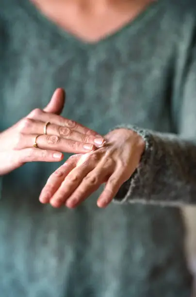 Cropped shot of a woman rubbing ointment on her painful hand