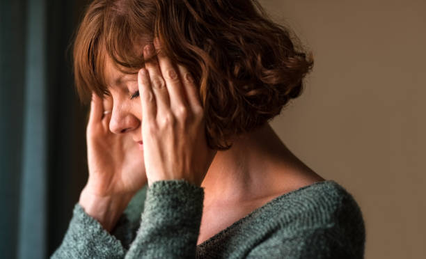 Woman in pain Close-up shot of a woman suffering from a headache and rubbing her temples at home head in hands stock pictures, royalty-free photos & images