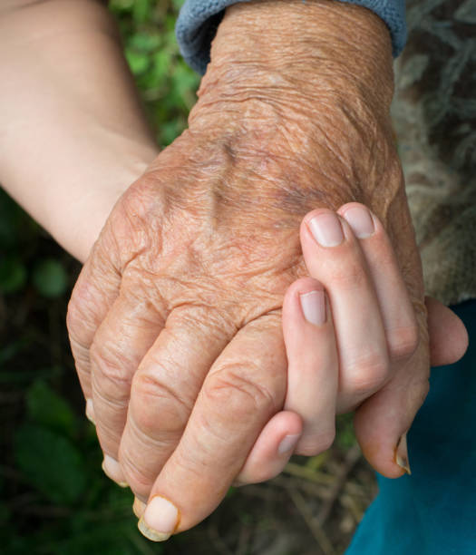 istock Old and young woman holding hands together 1175064331
